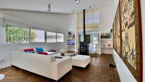 A spacious living room with a white sofa, a fireplace, and a large painting on the wall. - Modern Villa with pool and garden Finca La Xara (Pedreguer)