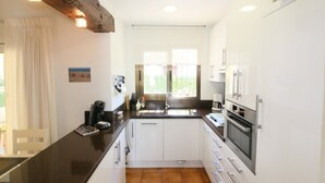 Una cocina moderna con armarios blancos, encimera negra y viga de techo de madera.