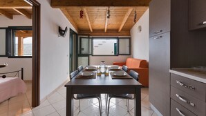 Un coin repas avec un plafond en bois, une table dressée pour quatre personnes et un canapé en arrière-plan.