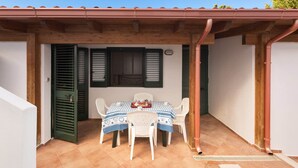 Une terrasse couverte avec une table et des chaises, un plafond en bois et un sol carrelé.