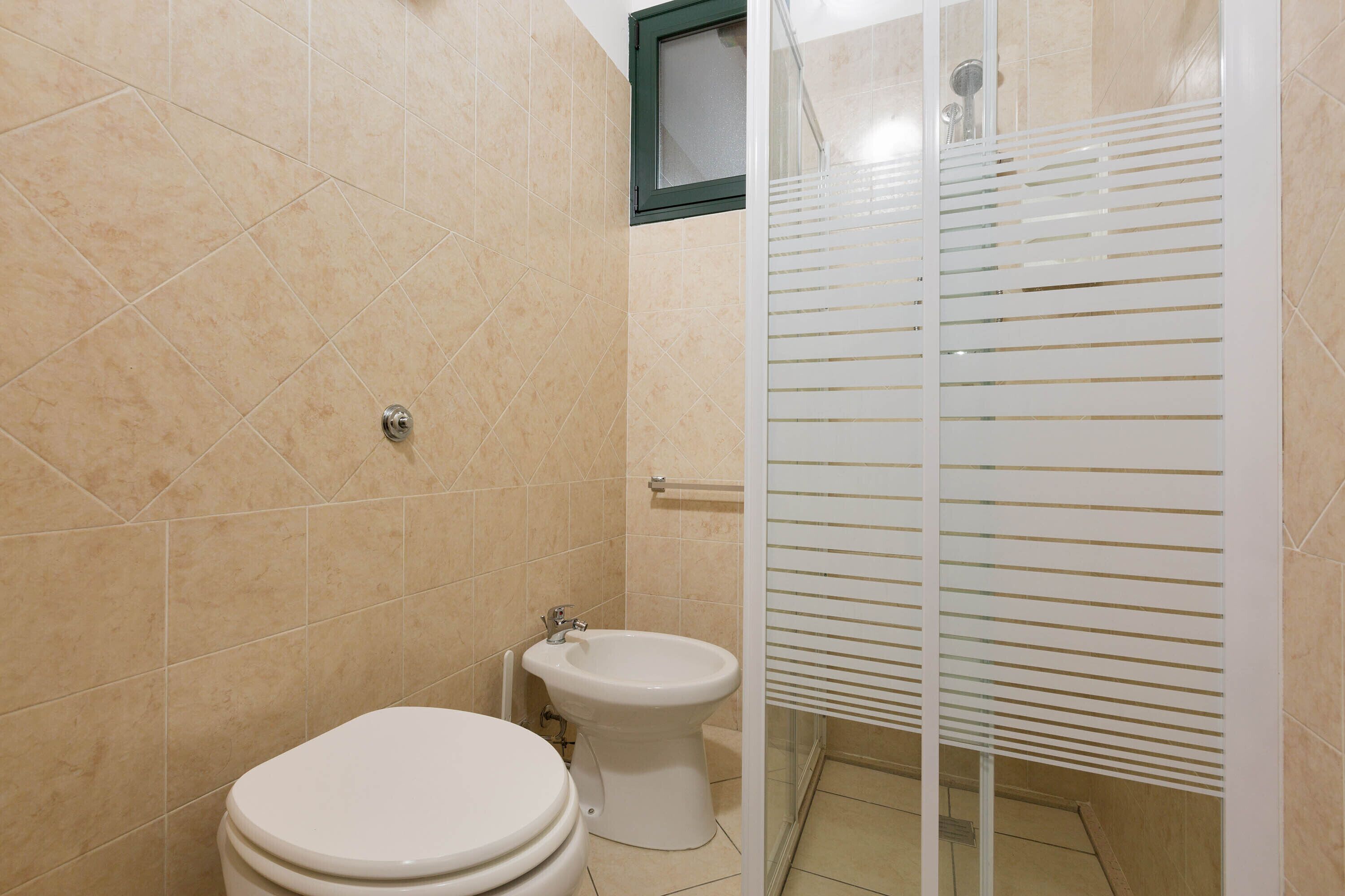 Ein Badezimmer mit Toilette, Bidet und Dusche mit Milchglasüren.