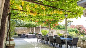 An outdoor patio with a table and chairs, surrounded by greenery and stone walls. - Property with a swimming pool, rare find within walking distance to Old Town (Dubrovnik)