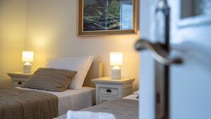 A hotel room with two beds, each with a pillow and a bedside lamp. There is a painting on the wall above the beds. - Property with a swimming pool, rare find within walking distance to Old Town (Dubrovnik)