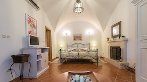 A bedroom with a bed, bedside lamps, a fireplace, a desk with a computer, and a decorative tray with candles. - Property with a swimming pool, rare find within walking distance to Old Town (Dubrovnik)