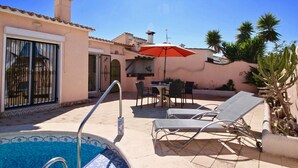 Zona junto a la piscina con piscina, sillones de descanso, una mesa con sillas y una sombrilla.