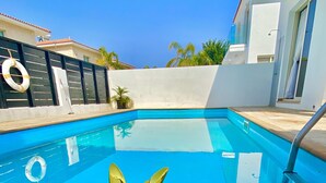 A swimming pool with a golden pineapple decoration and a glass of lemonade with lemon slices.