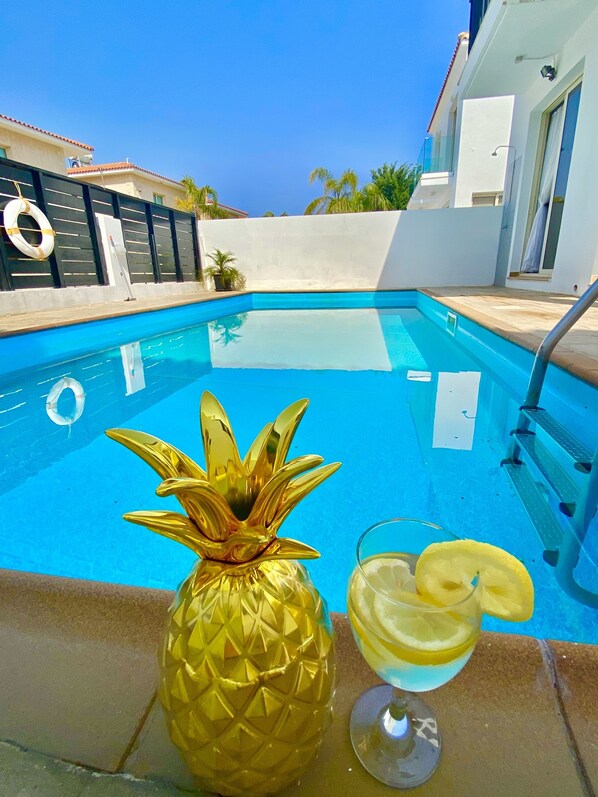 A swimming pool with a golden pineapple decoration and a glass of lemonade with lemon slices.
