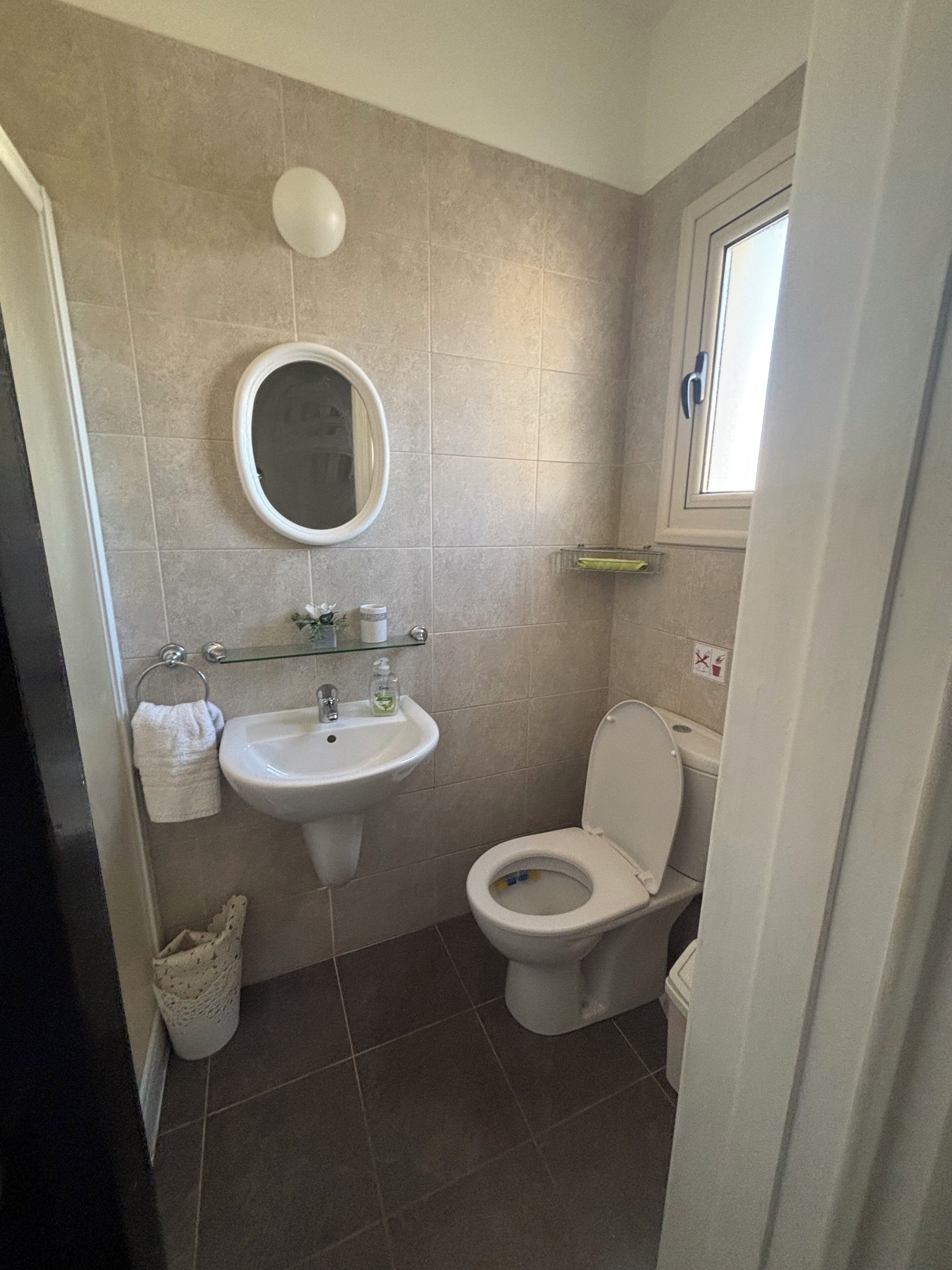 Ein Badezimmer mit Waschbecken, Spiegel, Toilette und Fenster.