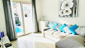 A living room with a sofa, a coffee table, a lamp, and a painting of flowers.