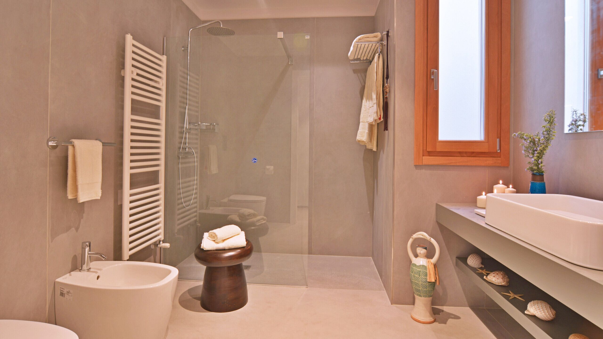 A modern bathroom with a shower, toilet, bidet, and sink.