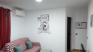Una sala de estar con un sofá a cuadros, una mesita de centro y un aire acondicionado instalado en la pared.