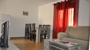 Una sala de estar con un sofá, una mesa de centro, un televisor y un comedor con sillas y una mesa.