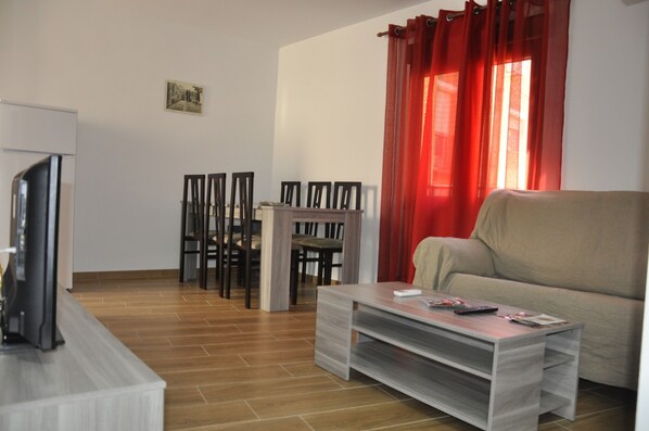 A living room with a sofa, a coffee table, a TV, and a dining area with chairs and a table. - COMPLETELY RENOVATED HOUSE WITH FREE WIFI (TOLEDO)