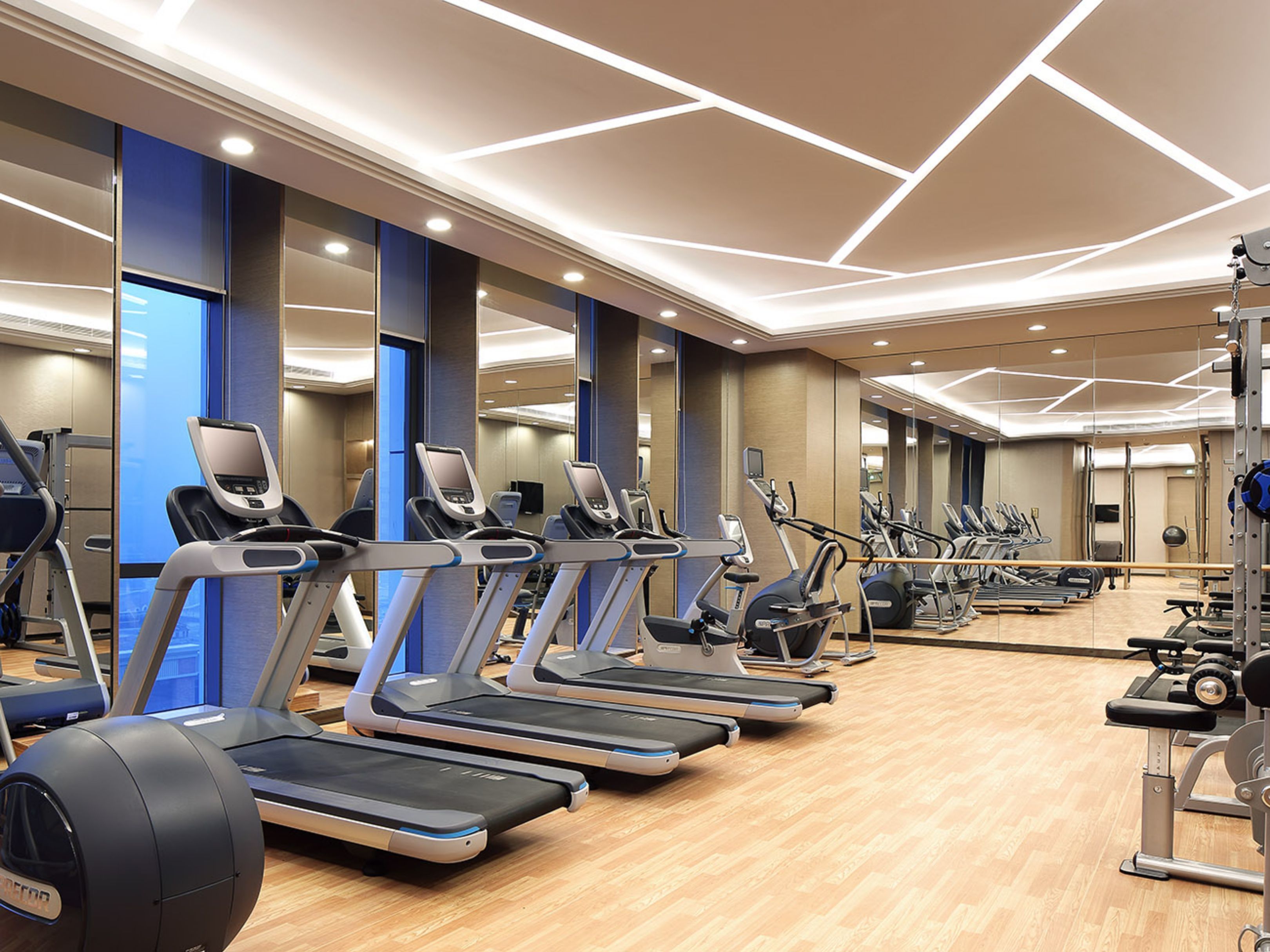 Une salle de sport équipée de plusieurs tapis de course, de vélos d’exercice et d’appareils de musculation.