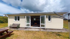 A small, single-story house with a patio area, a bench, and a clothes drying rack. - F26 Porthia, Riviere Towans (Hayle)