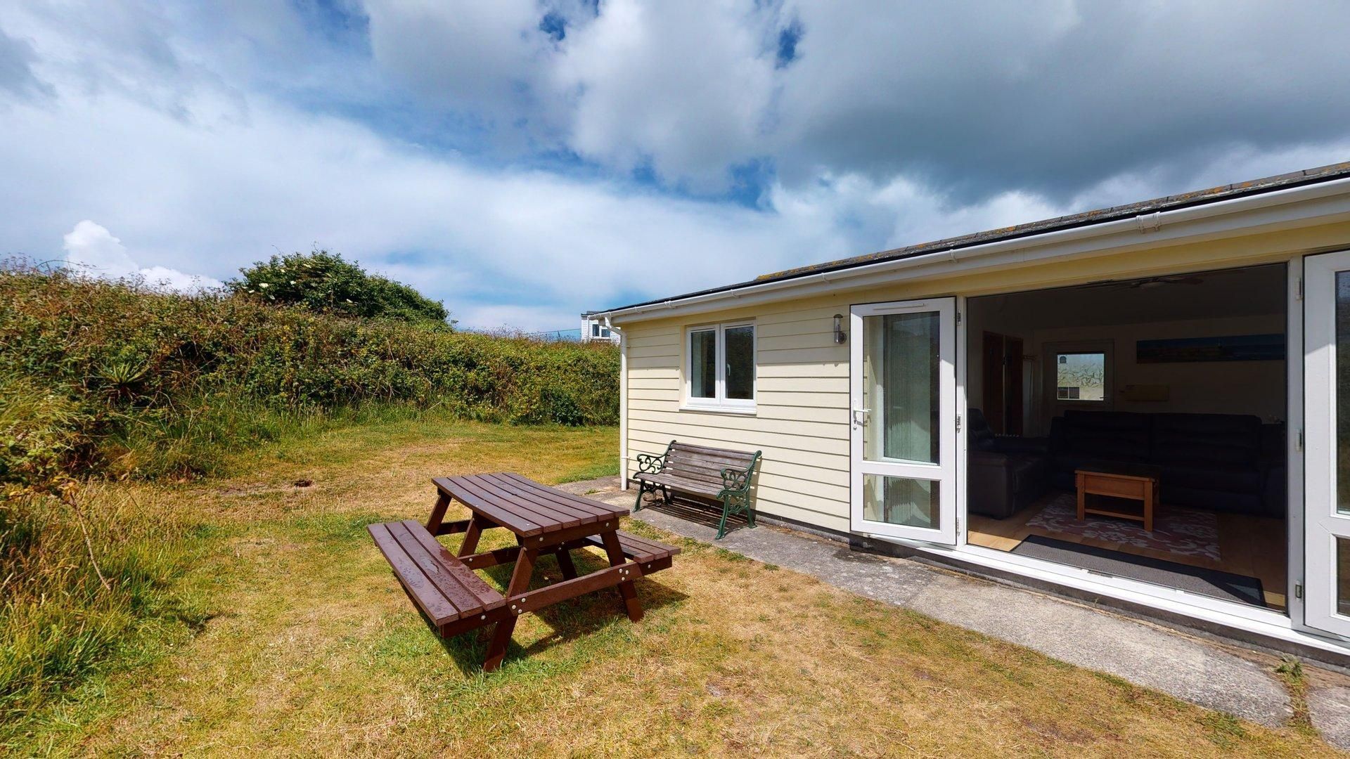 A single-story house with a patio area featuring a wooden table and bench.