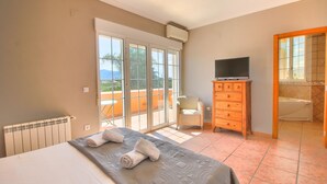 A hotel room with a bed, a TV, a wooden cabinet, and a bathroom with a bathtub. - Quiet Villa with wifi and air conditioning Finca Las Ranas (Denia)