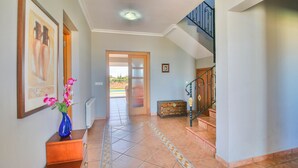 A hallway with a tiled floor, a wooden bench, a staircase with a wrought iron railing, and a door leading to an outdoor area. - Quiet Villa with wifi and air conditioning Finca Las Ranas (Denia)