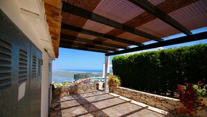 Un espacio al aire libre cubierto con paredes de piedra, vistas al mar y plantas en macetas.