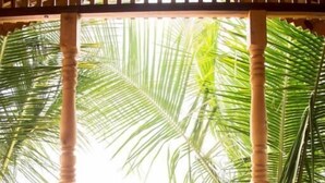 A room with a patterned floor, a wooden railing with geometric designs, and a view of palm trees. - Ramsons Resort (Canacona)
