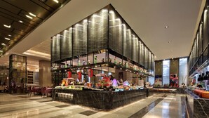 En moderne hotellobby med et centralt displayområde, der viser forskellige genstande, samt et siddeområde med borde og stole.