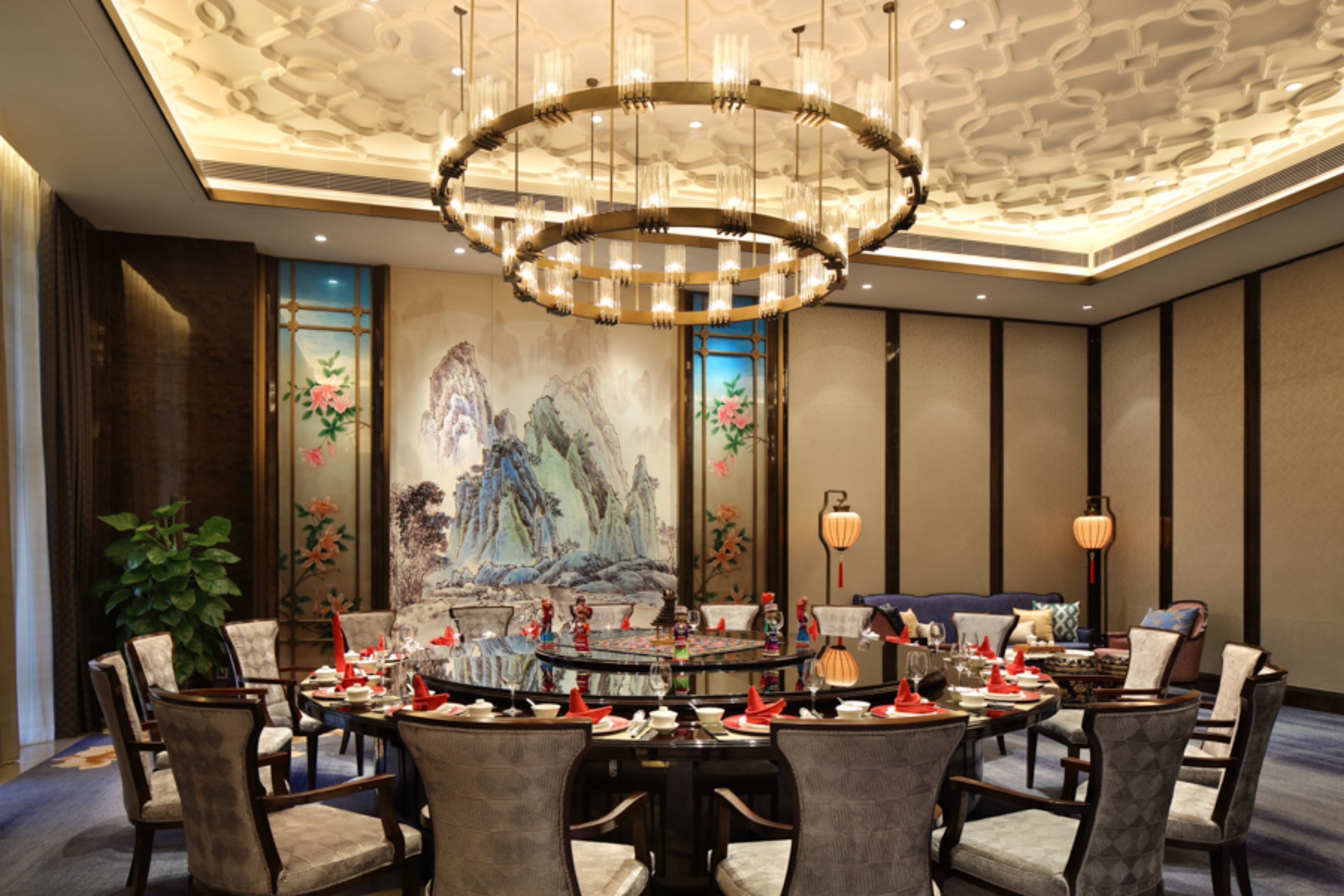 A dining area with a round table, chairs, and a chandelier.
