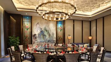 A dining area with a round table, chairs, and a chandelier.