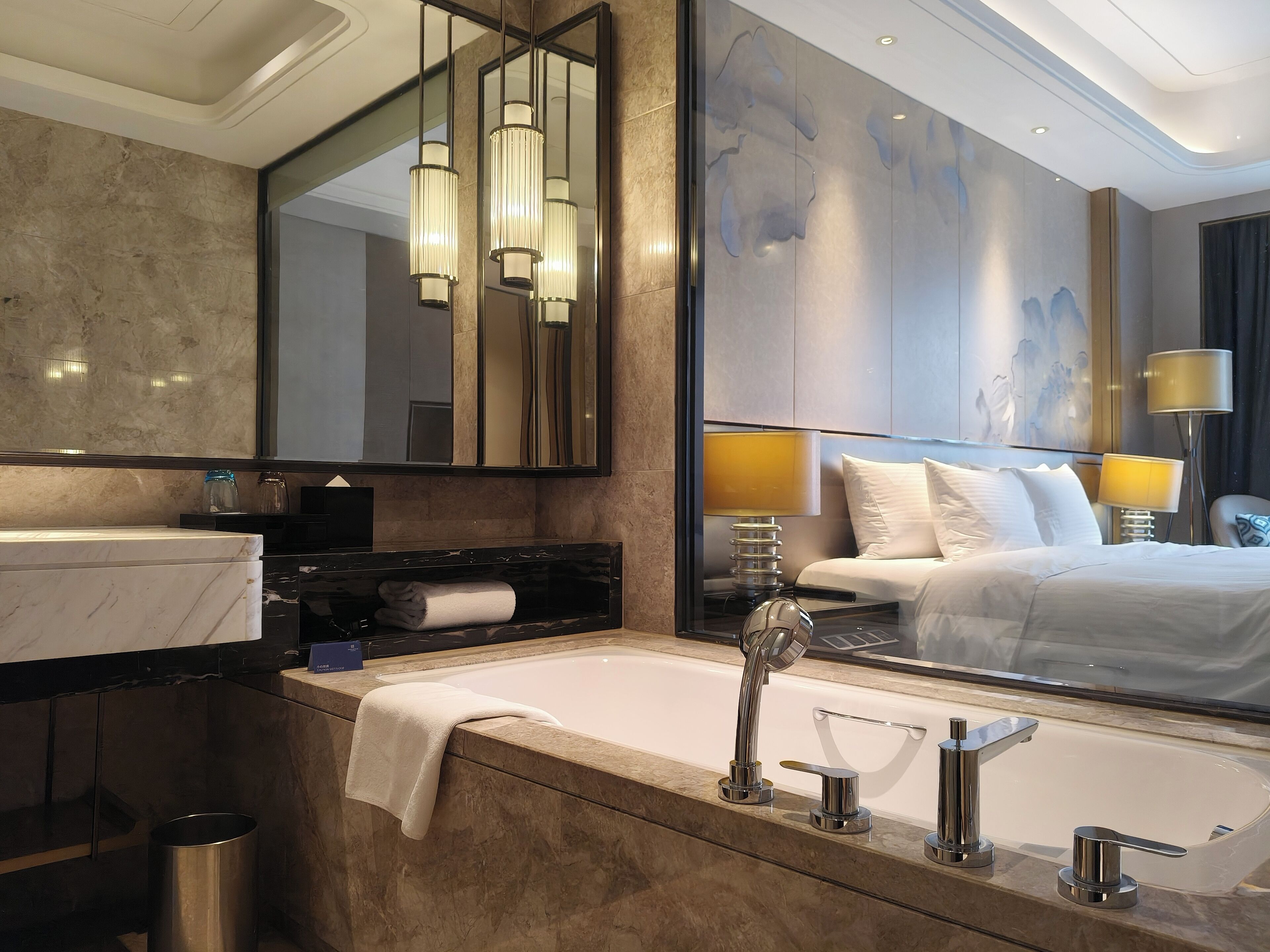 A modern bathroom with a large mirror, a bathtub, and a vanity with a towel.
