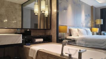 A modern bathroom with a large mirror, a bathtub, and a vanity with a towel.