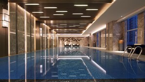 En moderne indendørs swimmingpool med en klar vandoverflade, omgivet af marmorvægge og et stilrent loftsdesign.
