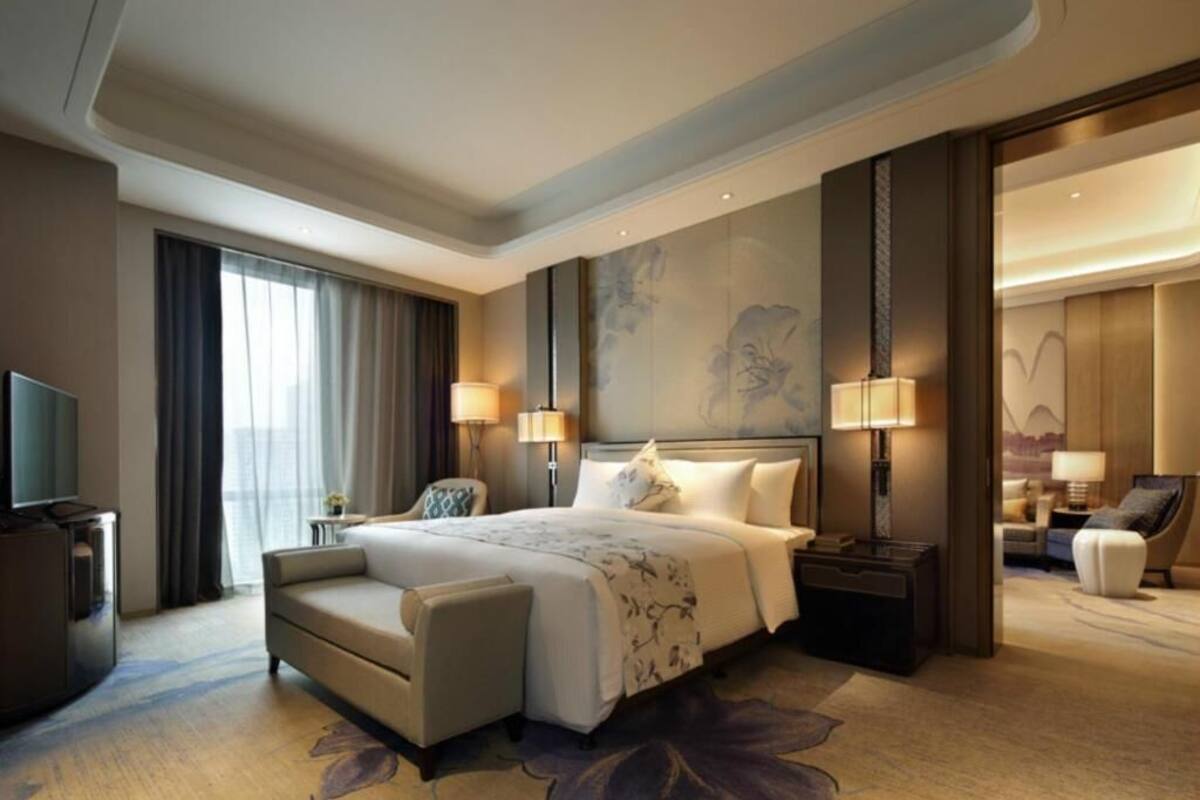A spacious hotel room with a large bed, a sofa, a TV, and a desk.