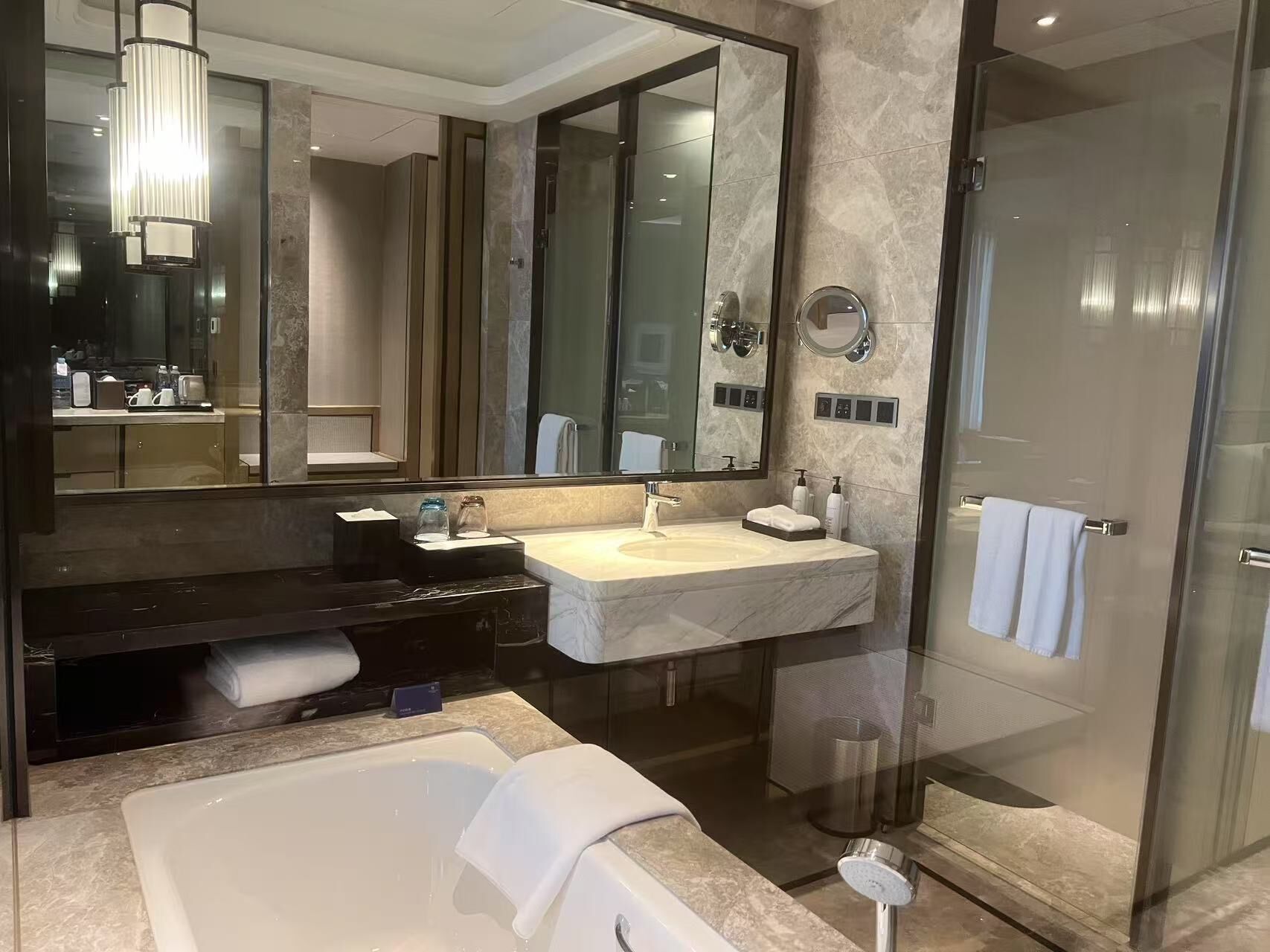 Une salle de bain moderne avec un grand miroir, une baignoire, un lavabo et une douche.