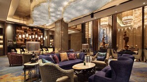 En luksuriøs lobby med en imponerende lysekrone, komfortable møbler og et veloplyst barområde.