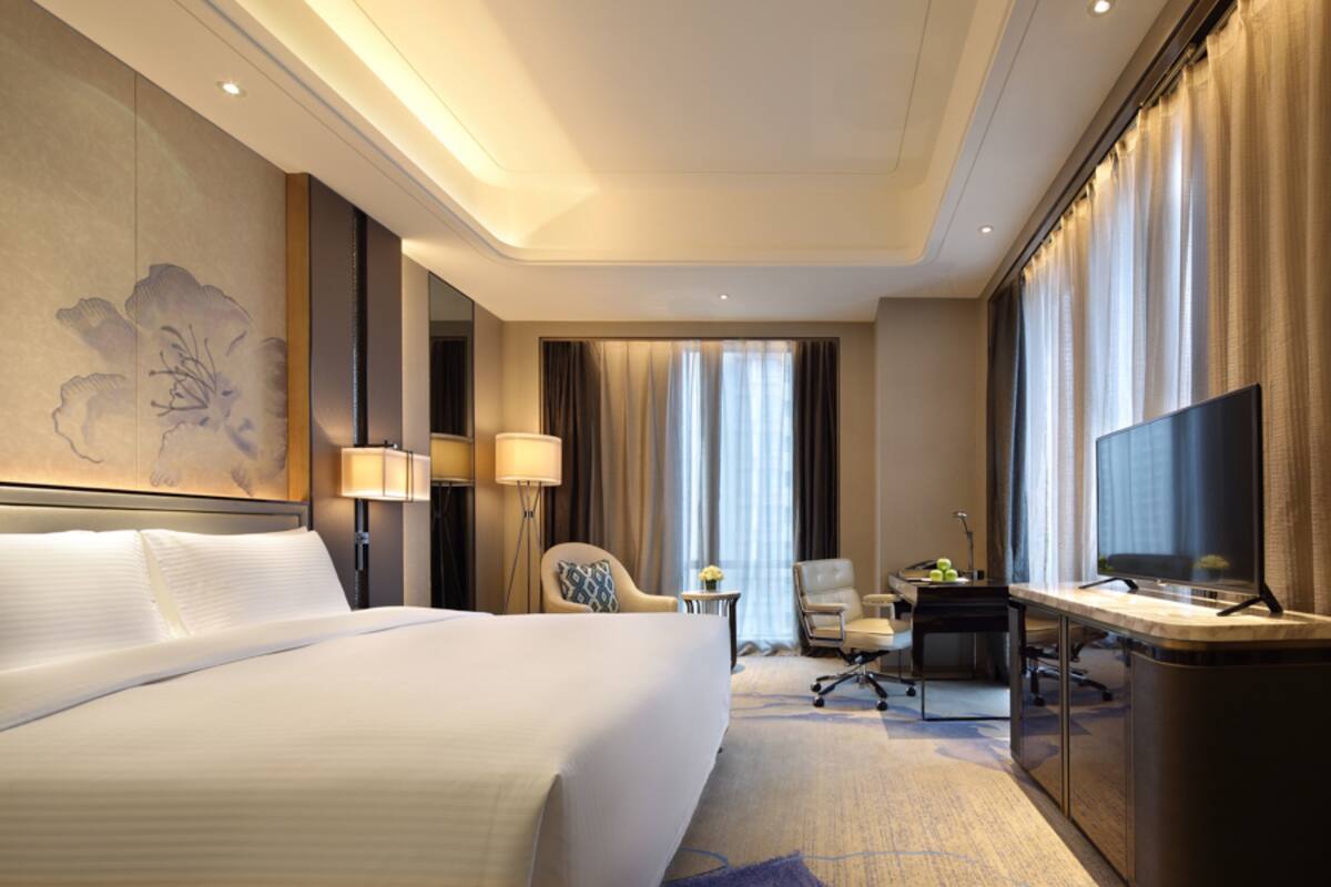 A hotel room with a large bed, a desk with a television, and a seating area with two chairs.