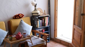 Een gezellige woonkamer met een bank, een klein tafeltje en een boekenplank.