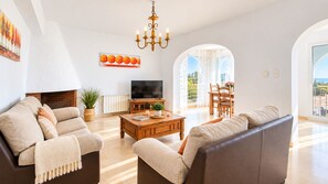 Un salon spacieux doté d’une cheminée, d’un téléviseur et d’une grande fenêtre donnant sur l’extérieur.
