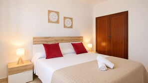 Une chambre d’hôtel comprenant un lit, deux tables de chevet, une armoire en bois et deux éléments de décoration murale.
