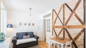 A modern living room with a grey sofa, white table, and a rustic wooden wall. - I-Centre of old Lisbon in first floor (Lisboa)