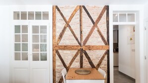 A room with a wooden table and chairs, a white door, and a brick-patterned wall with wooden beams. - I-Centre of old Lisbon in first floor (Lisboa)