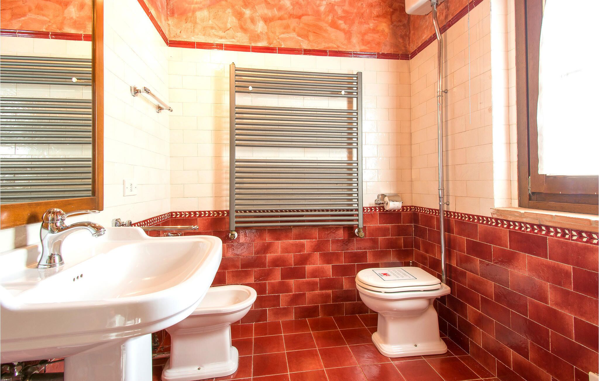 Ein Badezimmer mit Waschbecken, zwei Toiletten, einem Handtuchhalter und einer Dusche.