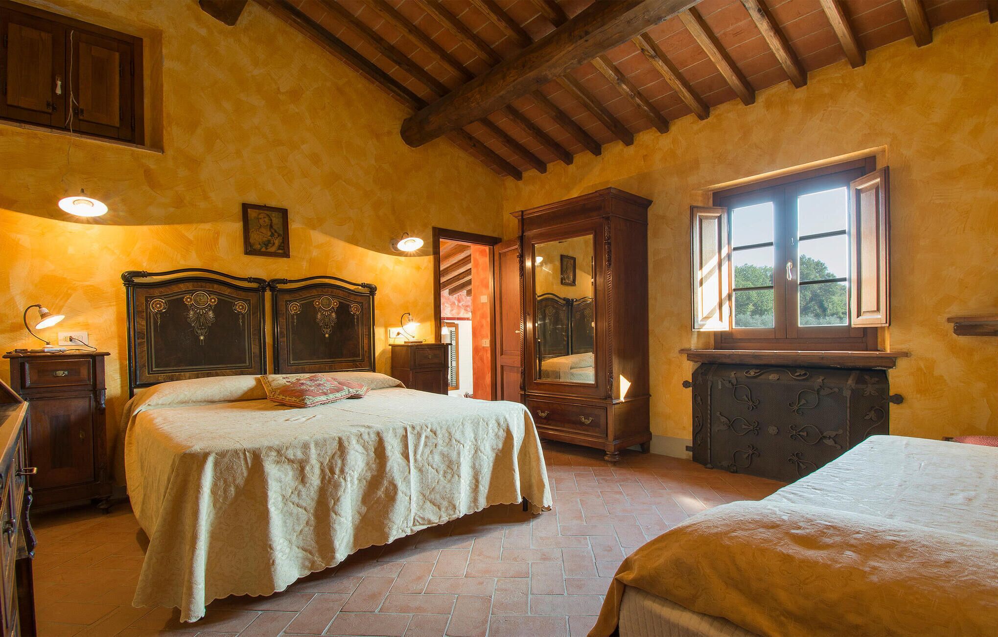 Une chambre avec deux lits, des meubles en bois, un grand miroir et une fenêtre donnant sur un beau paysage.