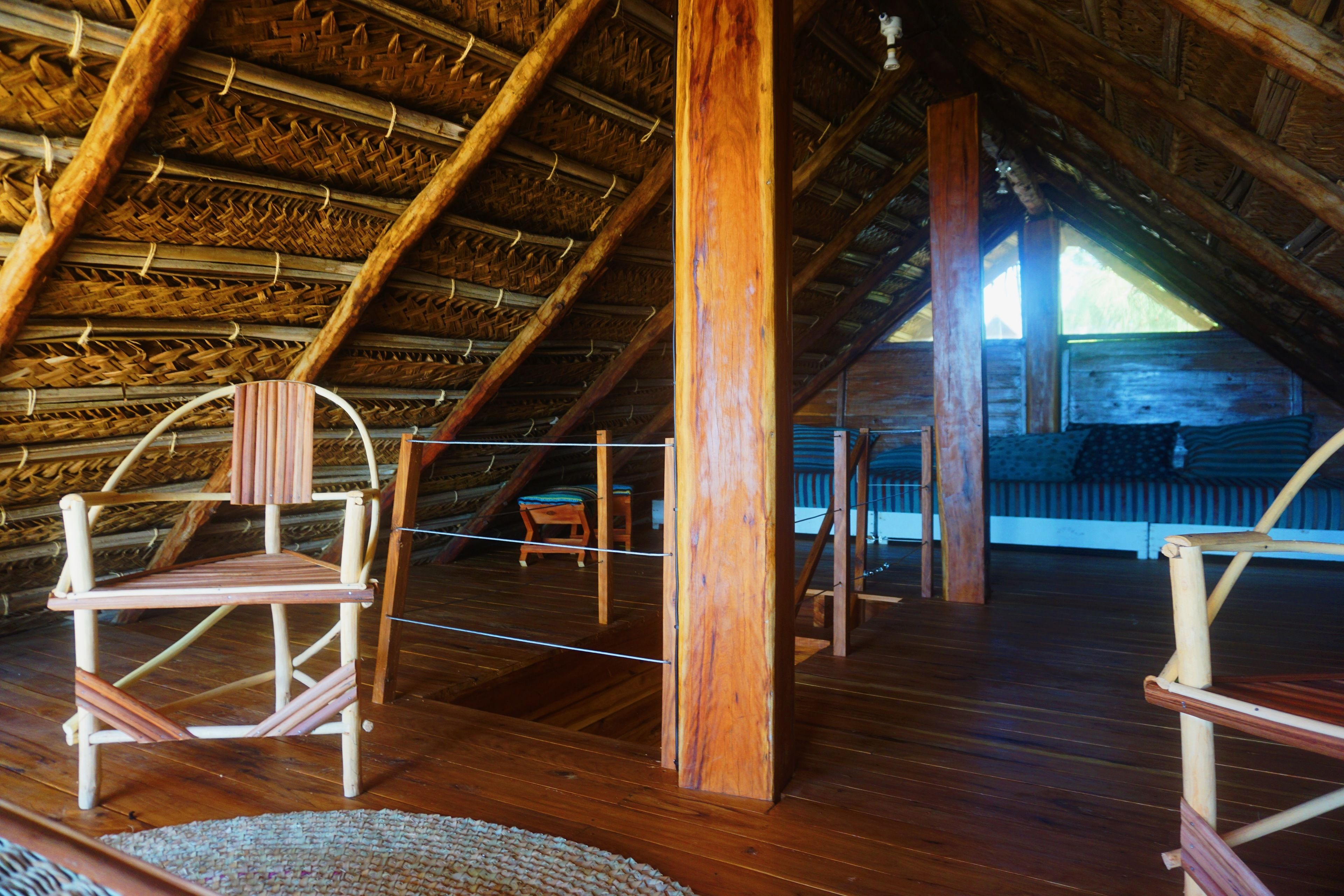 An attic room with wooden beams, a high ceiling, and a rustic wooden chair.