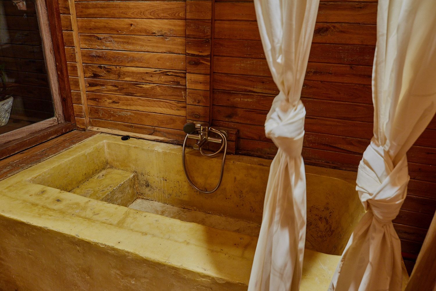 Uma cabana de madeira com banheira e janela.