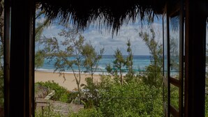 A view from inside a building looking out to a beach with trees and the ocean. - Casa Algodoal (Tofo)
