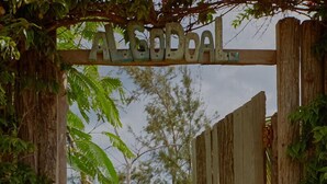 A wooden gate with the word "ALSOAL" above it, leading to a pathway. - Casa Algodoal (Tofo)