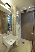 Un baño moderno con un lavamanos grande, cabina de ducha de vidrio y un espejo.