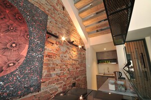 Una cocina moderna con pared de ladrillo, vigas de madera y encimera negra con electrodomésticos.
