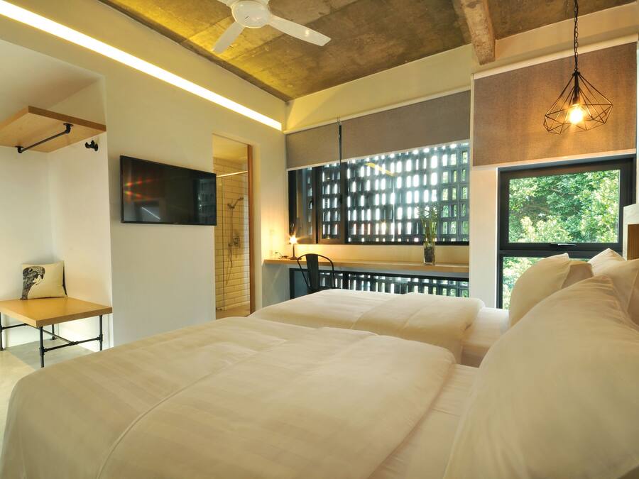 A modern bedroom with a large bed, a desk, and a TV mounted on the wall.