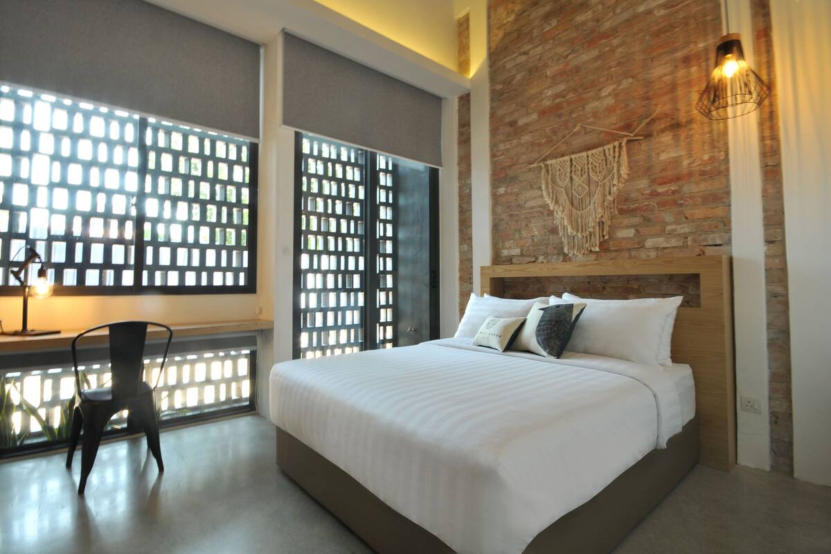 Un dormitorio moderno con una cama grande, un escritorio con silla y una pared de ladrillo.