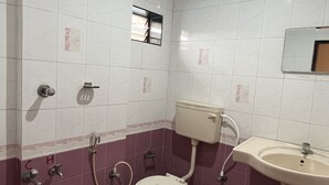 A bathroom with a toilet, sink, and shower. - Hotel Gangasagar (Bengaluru)